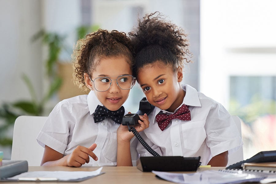 Two young girls explore making calls using a landline phone.